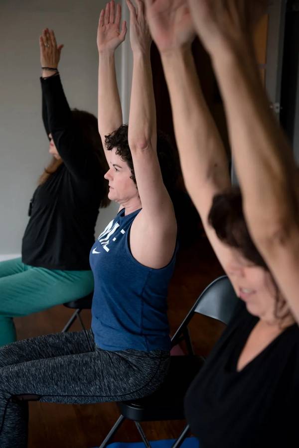 A group of people sitting in chairs doing yoga.