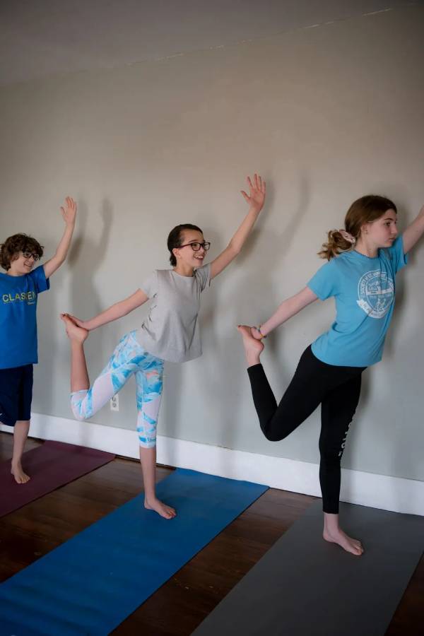 Three children are practicing yoga in a room.