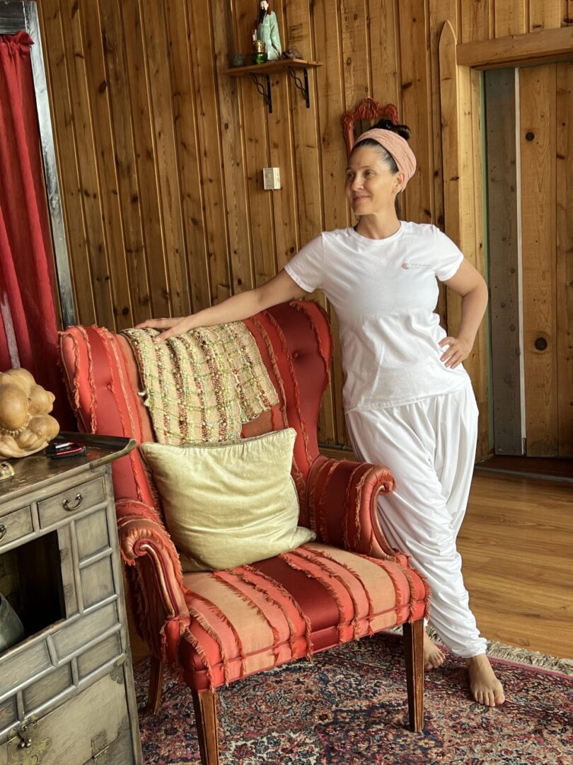 A woman standing in front of a chair with pillows.